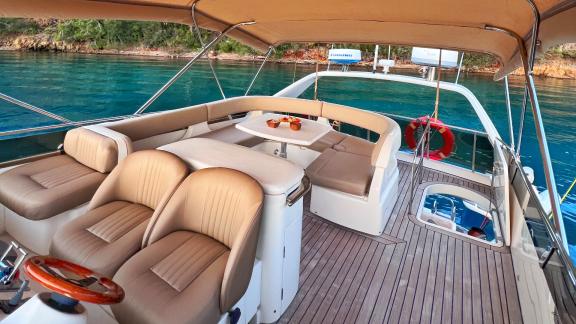 The flybridge seating area of the motor yacht Hadron is equipped with comfortable seats and a table.